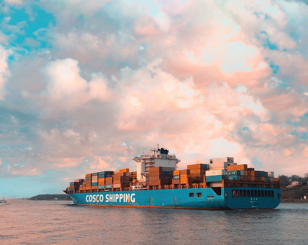 blue cargo ship on sea under cloudy sky during daytime